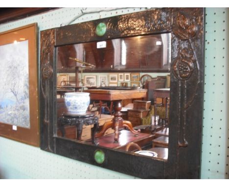 A circa 1880s wall mirror, the beaten pressed copper frame decorated with stylized lilies and Ruskin-type apple green enamel 