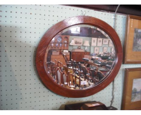 An Edwardian oval oak wall mirror with bevelled plate.
