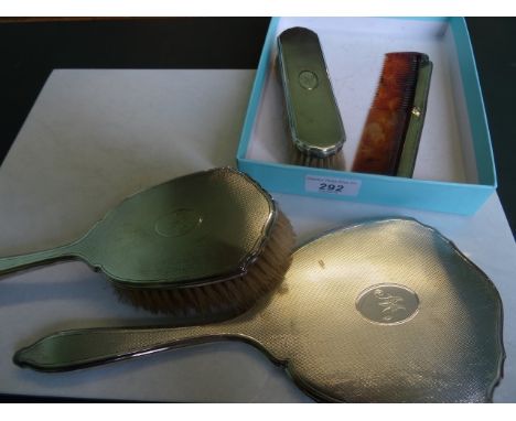 A silver back hand mirror, together with two brushes and a comb.