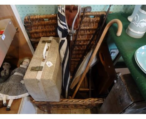 A wicker basket containing various items, including: a Brexton picnic hamper, shooting stick, walking canes, hickory shafted 