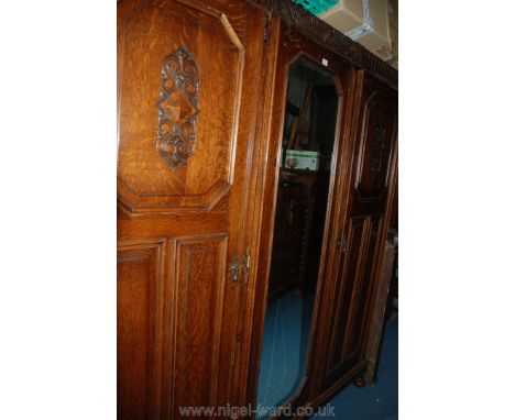 A 1940's Jacobean style triple Wardrobe with moulded cornice, over central full length bevel plated mirrored door, flanked by