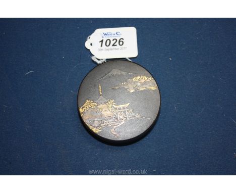A Japanese lady's compact, black enamel with a landscape scene of Mount Fuji in silver and gold inlay, marks to the base, 2 1