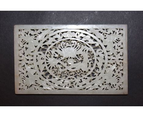A CHINESE JADE PLAQUE, with carved and pierced decoration of a dragon, bats, phoenix and foliage, 5.6in x 3.5in.
