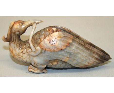 A 20TH CENTURY CHINESE JADE LIKE CARVING OF A MYTHICAL BIRD, clasping a piece of lingzhi fungus in its beak, 6in long.