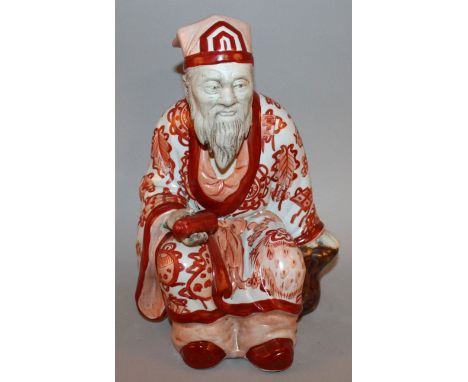 A CHINESE IRON-RED DECORATED FIGURE OF A SEATED SAGE, bearing a scroll in one hand, the base unglazed and with an impressed s