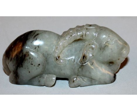 A 20TH CENTURY CHINESE GREY JADE CARVING OF A SEATED RAM, the stone with darker inclusions, 3in long.