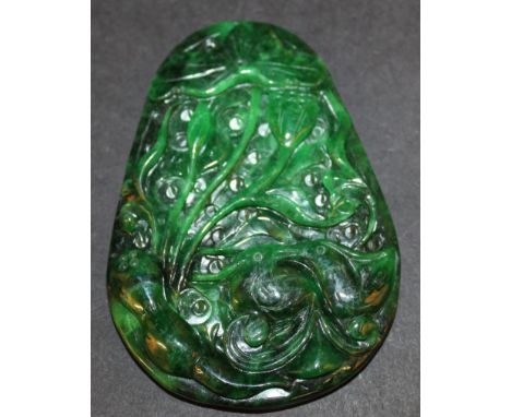 A CHINESE SPINACH-GREEN JADE-LIKE PENDANT, decorated in high relief with lotus, 3.5in high.