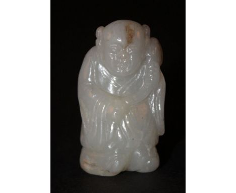 A SMALL CHINESE JADE FIGURE OF A BOY, carved holding a peach frond, the pale stone with darker inclusions, 2in high.