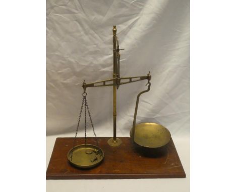 A brass balance scales on rectangular mahogany base and three small brass weights