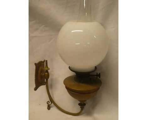 A wall mounted brass oil lamp by Hinks with curved bracket and opaque glass shade
