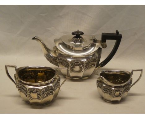 An Edward VII silver three-piece tea set comprising oval tea pot with raised scroll decoration, hinged lid and ebonised handl