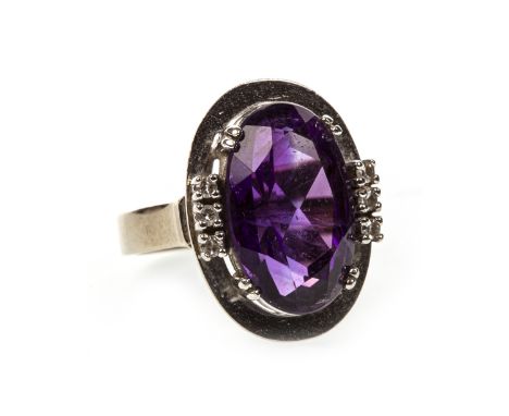 PURPLE GEM SET AND DIAMOND RING, the oval purple gem measuring16x9mm, flanked by three round brilliant cut diamonds on either