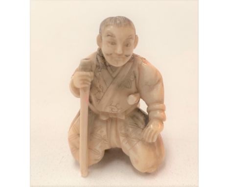 A Meiji period Japanese ivory carved netsuke in the form of a kneeling sage with staff, height 40mm.