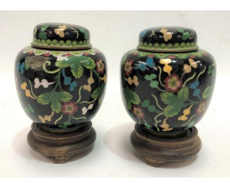 A pair of Chinese cloisonné  ovoid ginger jars and covers, foliate scroll decorated upon a black ground and on turned wood st