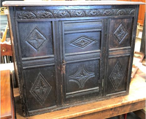 A reproduction oak low cupboard, the six panel front carved with flowerhead lozenges under an arcaded carved frieze, height 7