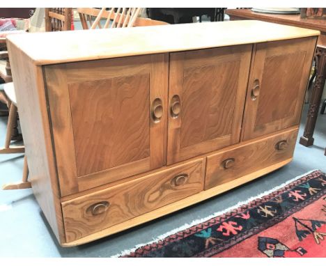 An Ercol blonde elm sideboard with three cupboards over two long drawers and on casters, width 129cm.