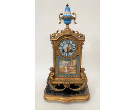 A gilt spelter cased two-train mantel clock with porcelain dial panel and finial, the 3in dial painted with a landscape and w