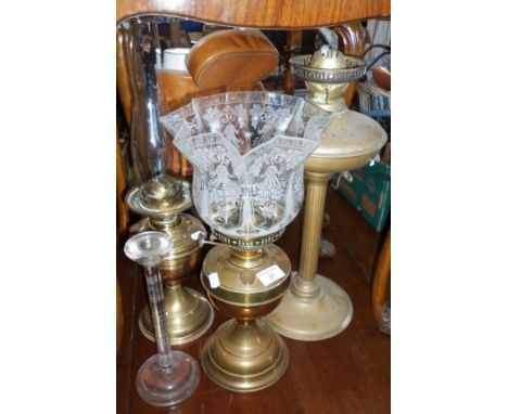 Three brass oil lamps and a glass candlestick