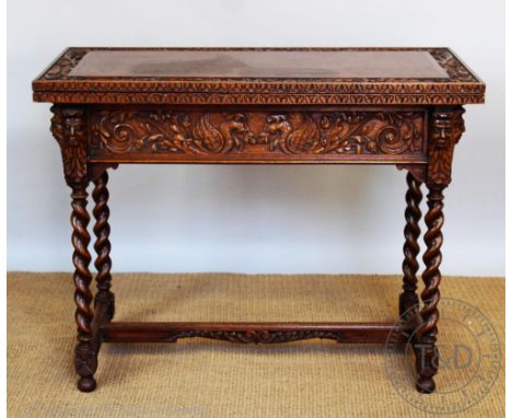 A late Victorian carved light oak folding tea table, elaborately carved with scrolling tendrils and green man motifs, on spir