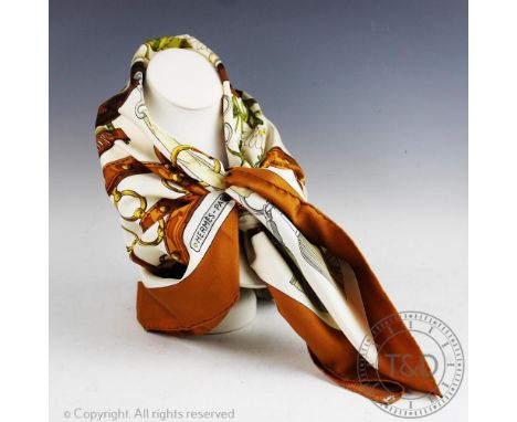 An Hermes Paris silk scarf, in 'Aux Champs' design, decorated with a central floral panel surrounded by a horse collar and ta