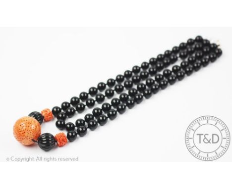 A carved coral coloured and black bead vintage necklace, designed as a two row bead necklace set with a large central coral b