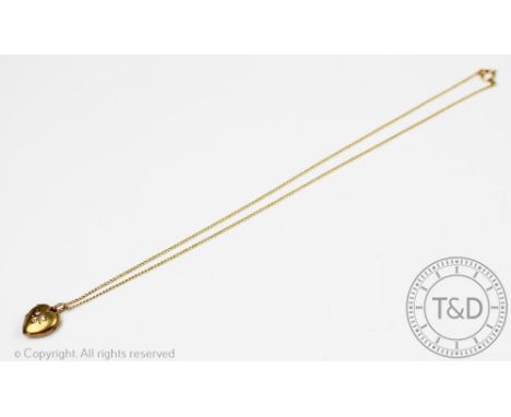 A diamond set heart shaped locket, the yellow metal locket stamped '15ct' and inset with three diamonds in a foliate design, 