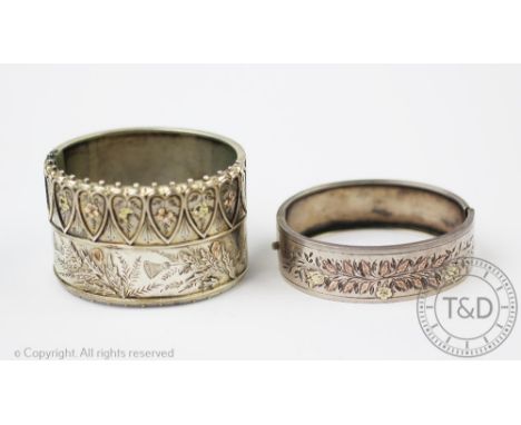 A Victorian silver hinged bangle, designed with a band of heart shaped designs above scrolling thistle foliage decoration and