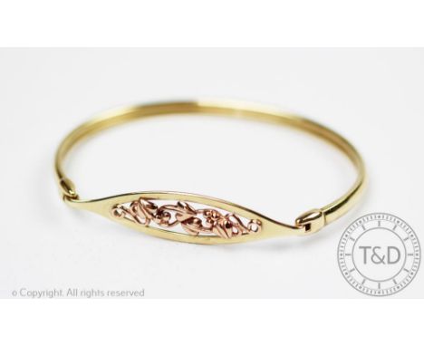 A 9ct yellow gold Clogau bangle, designed as an oval panel with sinuous foliage and plain tension bangle, gross weight 10.3gm