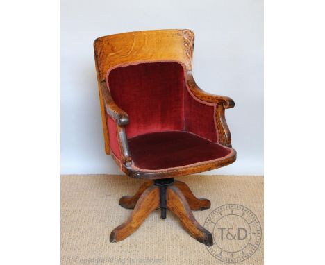 An Edwardian oak swivel desk chair, of vintage stye, with red upholstery and scroll end arms, on swivel base, 89cm H