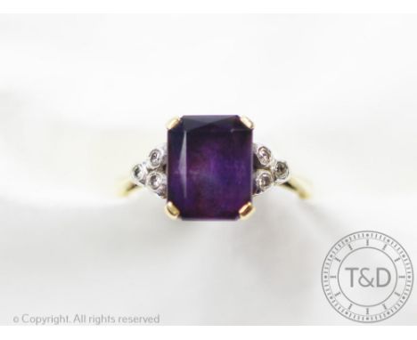 An amethyst and diamond ring, designed as a central rectangular, mixed cut amethyst flanked by a trio of diamonds to either s