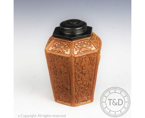 A late 18th century salt glazed stoneware octagonal tea caddy, each panel decorated in relief with formal scrolls and birds, 