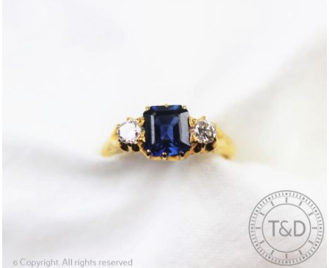 An untested sapphire and diamond three stone ring, designed as a central square shaped sapphire flanked by an old cut diamond