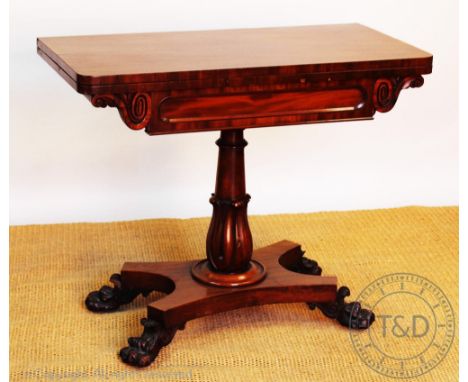 A William IV carved mahogany card table, with fold over top, on a baluster column, platform and paw feet, 77cm H x 91cm  W x 