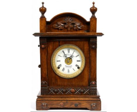 AN OAK MANTEL CLOCK, THE ENAMEL DIAL INSCRIBED FATTORINI AND SONS...BRADFORD, THE BREAK ARCHED PEDIMENT WITH TURNED FINIALS, 