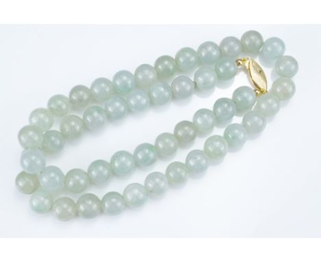 A PALE GREEN JADEITE SINGLE STRAND BEADED NECKLACE WITH 18KT YELLOW GOLD CLASP. The marquise-shaped clasp with hatched design