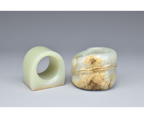 TWO CHINESE CELADON JADE ARCHER'S RINGS. A rounded ring with flat edge with russet colour, together with a carved and incised