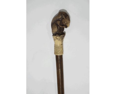 A wooden walking stick with carved bone collar and squirrel knop