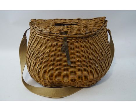 A vintage wicker fishing creel, with later canvas and leather strap, 35.5cm high x 48.6cm wide