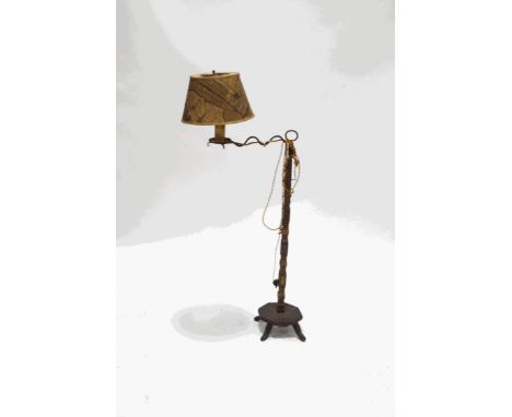 An unusual standard lamp with wrought iron arm on a carved and painted support, the octagonal base on four splayed legs, over