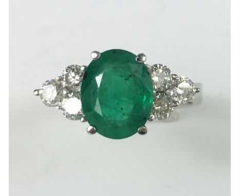 EMERALD AND DIAMOND RING
An 18ct white gold Emerald and Diamond ring with central oval Emerald flanked by three Diamonds to e