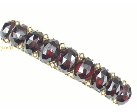 VICTORIAN GARNET AND PEARL BANGLE.
A large Victorian Garnet and Pearl bangle in yellow metal (tests as 9ct gold).  Nine large