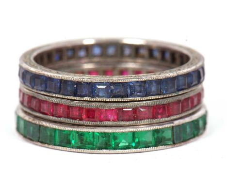 Three gemset eternity rings: to include a channel set sapphire ring with millegrain border and chased edges, and a matching r