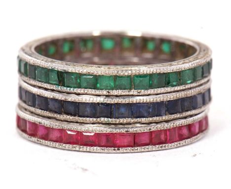 Three gemset eternity rings: to include a channel set sapphire ring with millegrain border and chased edges, and a matching r