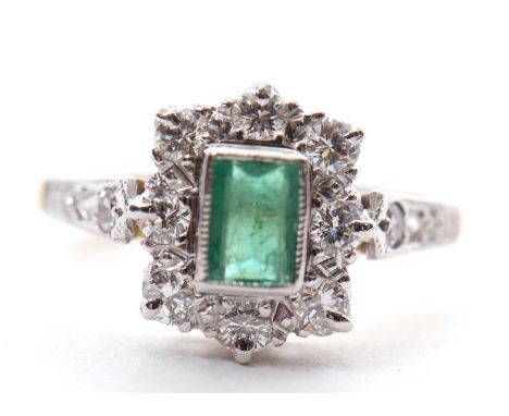 An emerald and diamond ring, the central step cut emerald in millegrain mount, surrounded by round brilliant cut diamonds, to