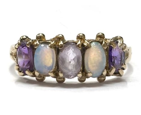 A 9ct amethyst and opal ring, the alternating oval facted amethysts and opal cabochons, claw mounted with plain band hallmark