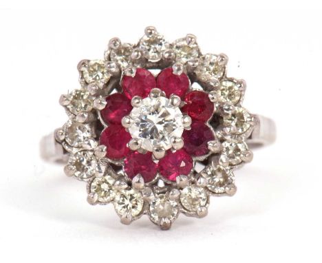 A ruby and diamond cluster ring, the central round brilliant cut diamond, surrounded by small round rubies and an outer ring 