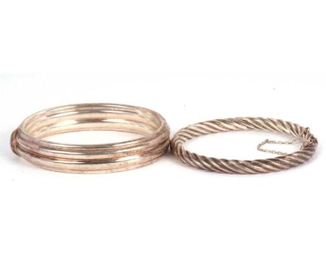 Two silver bangles: to include a hinged twisted bangle with integrated clasp stamped 925 with Sheffield import mark, with saf
