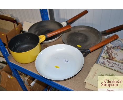 A cast iron and enamel saucepan and three frying pans