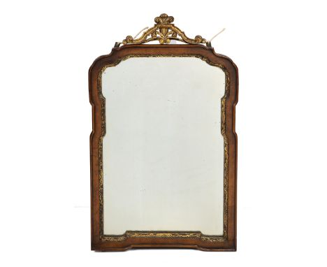 An 18th century style walnut and parcel gilt mirror The scrolling gilt crest above a shaped mirror plate and a relief carved 