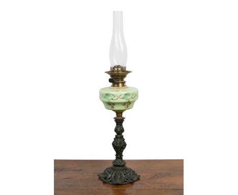 An antique oil lamp The green-painted cast iron base beneath a green glass reservoir decorated with cherries, and with a cast